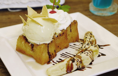 close up of homemade honey toast bread with vanilla ice creame and whipping cream on top serving with fresh banana with chocolate sauceの写真素材