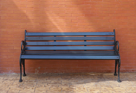 Black painted timber bench on the floor outdoor with red brick wall backgroundの写真素材