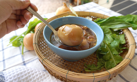 Human hand holding sppon with Eggs stewed serving on the basketの写真素材