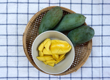 yellow mangoes ready to eat in the bowl and basket  with green mangoes background