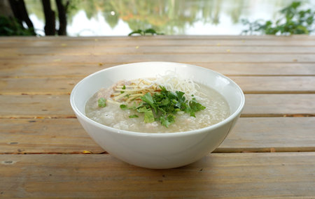 Homemade Pork porridge with ginger and coriander with timber background