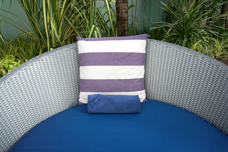 purple and white stripe cushion on blue beach bed with grey plastic woven backing