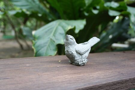 litlle bird sculpture on the timber plank with nature backgroundの写真素材