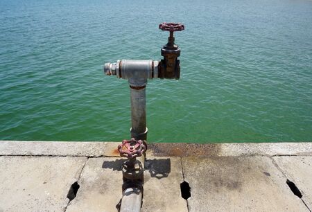 Red rusty water vault with sea backgroundの写真素材