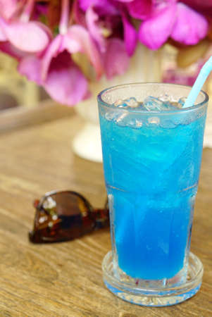Ice blue soda on timber table with sunglass and purple orchrid backgrondの写真素材