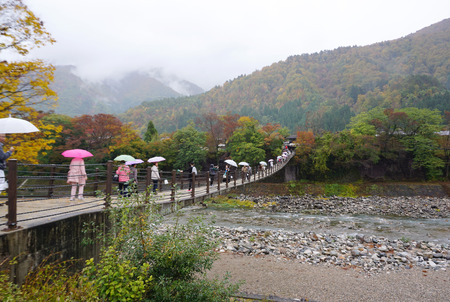 Shirakawa, Japan - 1 November,2016 : Tourist walking across thr bridge to Shirakawa go village during light rain in Japan on 1 November 2016 in Shirakawa, Japanのeditorial素材