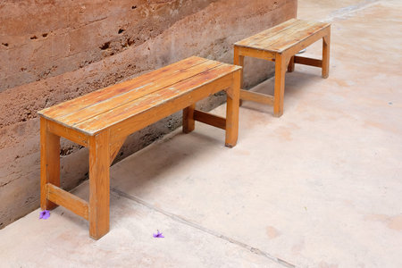 stained timber benches on the floor with sand stone wall background