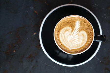 Beautiful latte art on Hot latte coffee with black cup and dark backgroundの写真素材