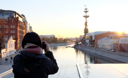 Woman traveler took a photo with camera at beautiful sunset at Moskva riverの写真素材