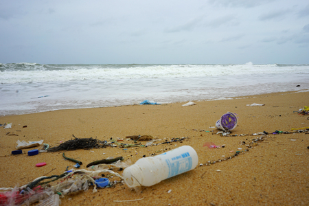 Plastic trash and garbage all over the beach with heavy wave and pine tree backgroundのeditorial素材