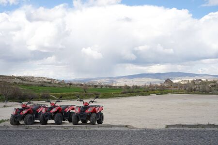 Red ATV bike park on the ground with beautiful unique landscape of fairy chimney in Goreme, Cappadociaの写真素材