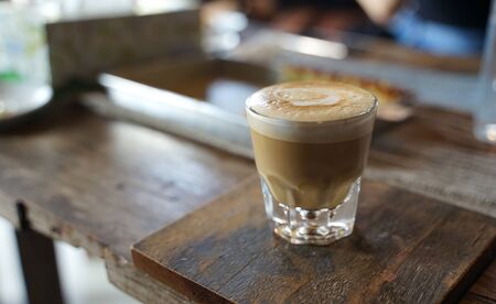 Close up hot coffee  latte in transparent glass on timber table background                               の写真素材