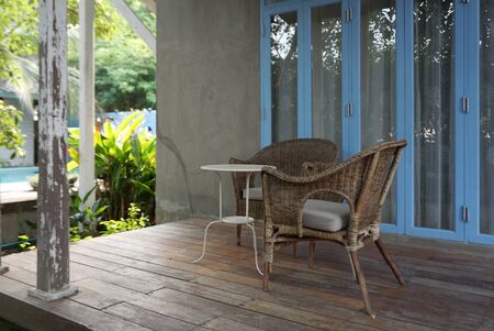 Vintage rattan chair with coffee table on patio with blue folding door backgroundの写真素材