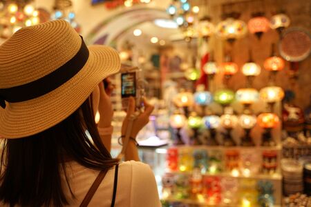 Asian woman wearing white hat taking photo with digital camera with shop front backgroundの写真素材