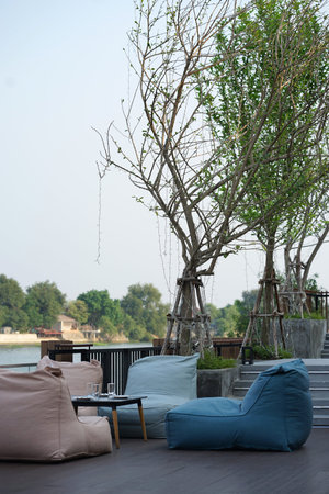 Bean bags seating and low timber for dining set with river background  outdoor