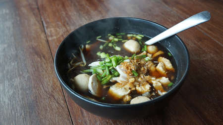 Traditional pork ball and Vietnamese Pork Sausage vermicelli  noodle soup Thai north eastern style on black bowl on timber tableの写真素材