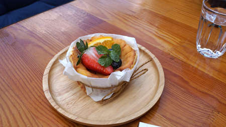 Burned cheese cake with strawberry and blueberry toppings serving on timber treyの写真素材