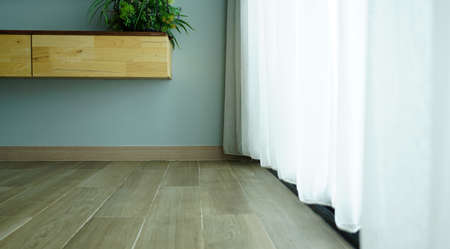 Interior view of the blue wall and timber floor tile with the sheer curtain and soft light on the side in the houseの写真素材