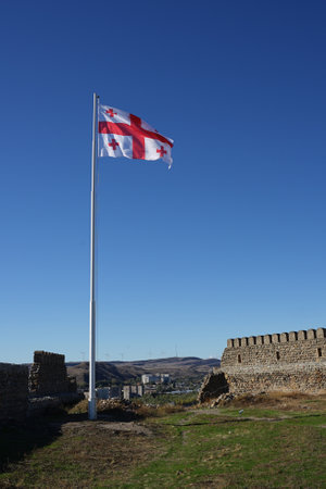 Gori, Georgia â22 October,2021 : Georgian flag on the pole on the beautiful old ruin of Gori fortress on the hill of Gori town on the sunny day â 22 October,2022 in Gori, Georgiaのeditorial素材