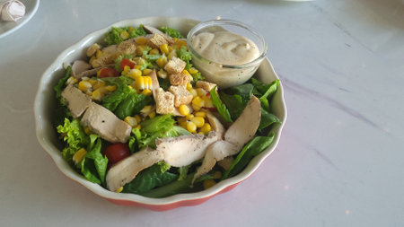 Chicken Caesar with green salad on white marble table top viewの写真素材