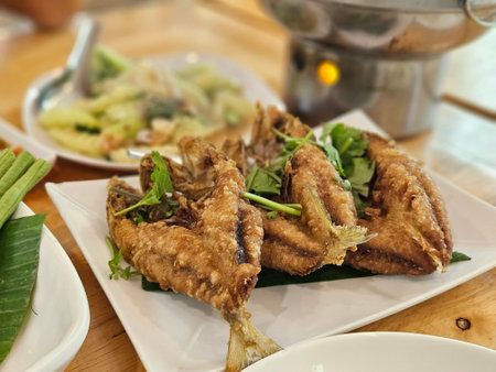 Deep fried mackerel in Thai style serving on white plate with food background.の写真素材