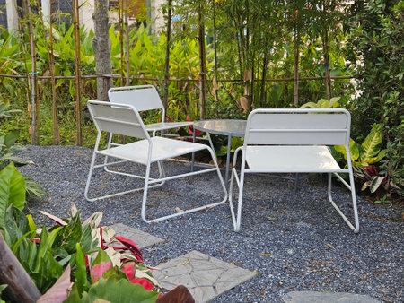 White metal outdoor furnitire in the tropocal garden surround with plants on the gravel floor outdoorの写真素材