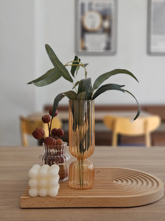 Green leaves artificial plants in the transparent vase on the timber trey decoration items in the cafe in nordic styleの写真素材