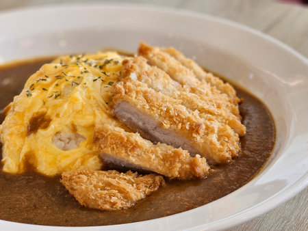 Japanese style deep fried pork with egg omelette curry rice on white plate on timber tableの写真素材