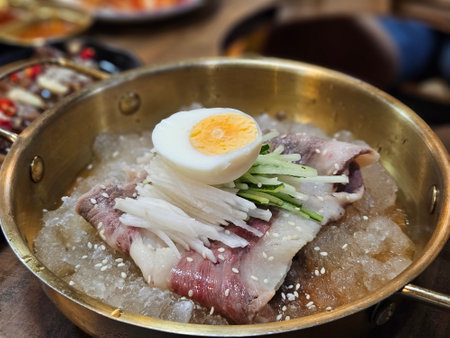 Traditional Korean noodle Pyongyang Naengmyeon serving in cold condition with beef on the table.の写真素材