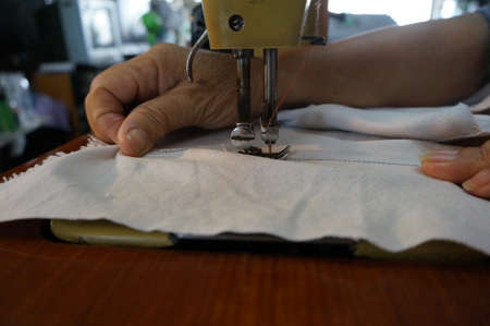 Closeup of lady's hand sewing cloth with old sewing machineの写真素材