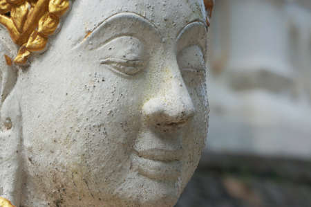 Close up face of stone statue of deity at a temple at northern of Thailandの写真素材