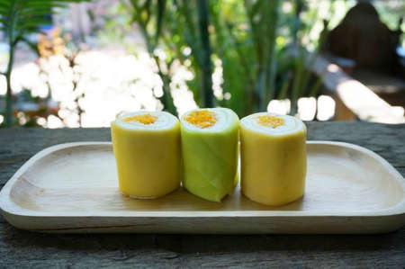 Colorful cream cake roll decorated with Thai dessert made from eggs inside on wooden table in natural background, close upの写真素材