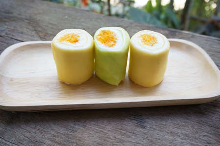 Colorful cream cake roll decorated with Thai dessert made from eggs inside on wooden table, close upの写真素材