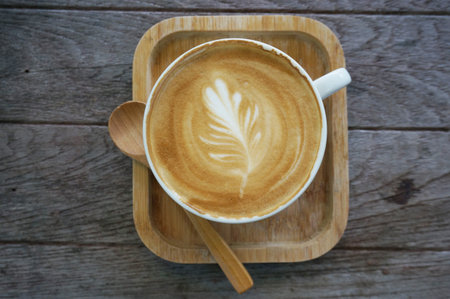 A cup of coffee in a white cup with wooden teaspoon on wooden background.の写真素材