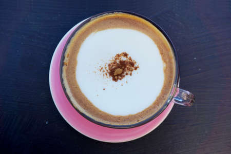 A cup of layer coffee in a glass cup on dark wooden background.の写真素材