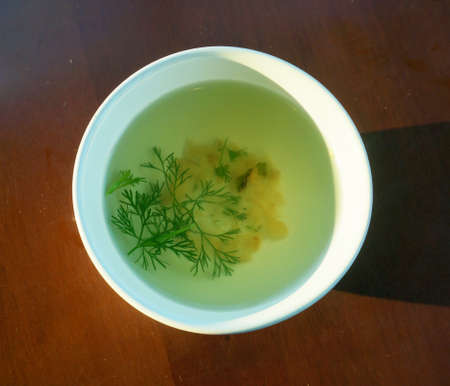 Bowl of broth and fresh vegetables on wooden backgroundの写真素材