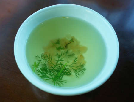 Bowl of broth and fresh vegetables on wooden backgroundの写真素材