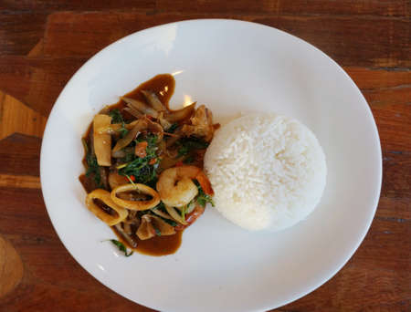 Asian food, Thai food and sea food, hot basil fried with squid and shrimp served with rice on wooden backgroundの写真素材