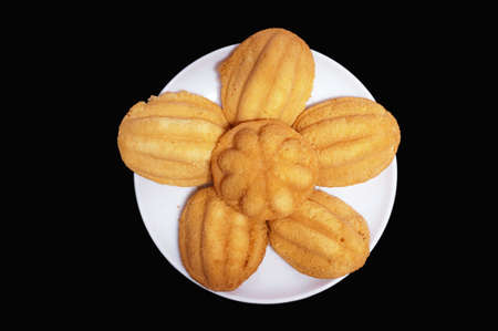 Madeleines cookies, Thai style, on white plate isolated on black backgroundの写真素材