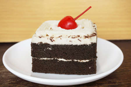 Colorful chocolate black forest cake decorated with cherry on wooden background, close upの写真素材