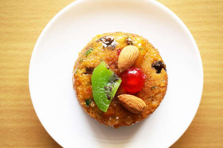 Colorful fruit cake decorated with almond, kiwi and cherry on wooden background, close upの写真素材