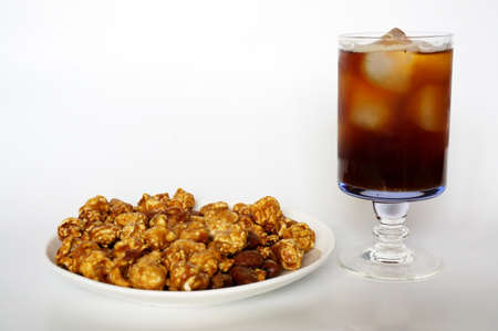 Caramel popcorn on white plate and cola on champagne glass isolated on white backgroundの写真素材