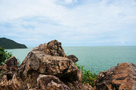 The rocky hill coast of the sea with blue sky and mountain at Chao Lao Beach, Chanthaburi, Thailand                               の写真素材