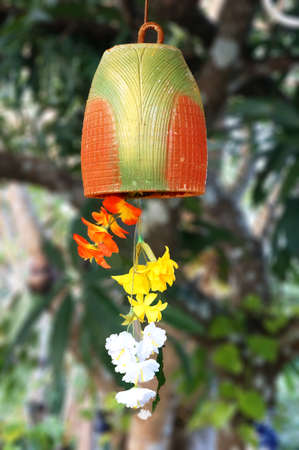 Ceramic Wind Chimes with cloth artificial flowers hanging in nature backgroundの写真素材