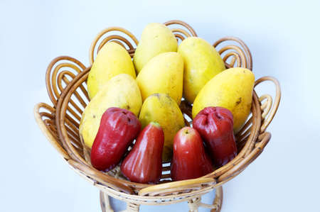 Set of fruit on rattan tray, rose apples fruit or chomphu and ripe mangoes isolated on white backgroundの写真素材