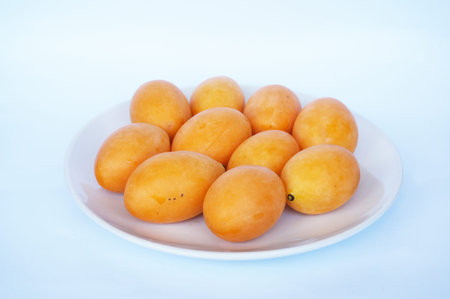 Close up of photo of very fresh Thai fruits, Marian Plum or Plango, on white plate isolated on white backgroundの写真素材