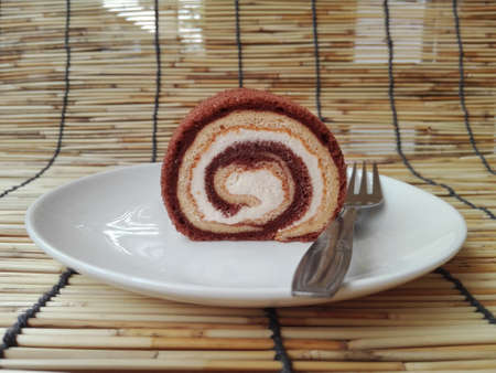 Colorful cream chocolate and vanilla layer cake roll on white plate isolated on white backgroundの写真素材