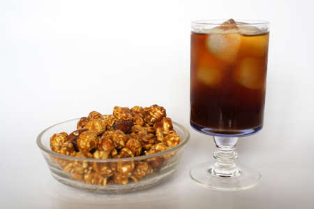 Caramel popcorn on white plate and cola on champagne glass isolated on white backgroundの写真素材