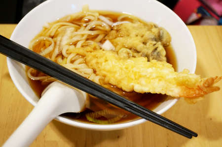 Asia - Asian eating food, Japanese food, Udon noodle in ramen soup with shrimp Tempura and Oyster mushroom Tempura, close upの写真素材