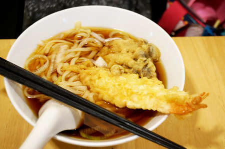 Asia - Asian eating food, Japanese food, Udon noodle in ramen soup with shrimp Tempura and Oyster mushroom Tempura, close upの写真素材